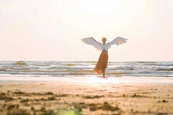 Winged angel by the sea and beach golden hour lighting
