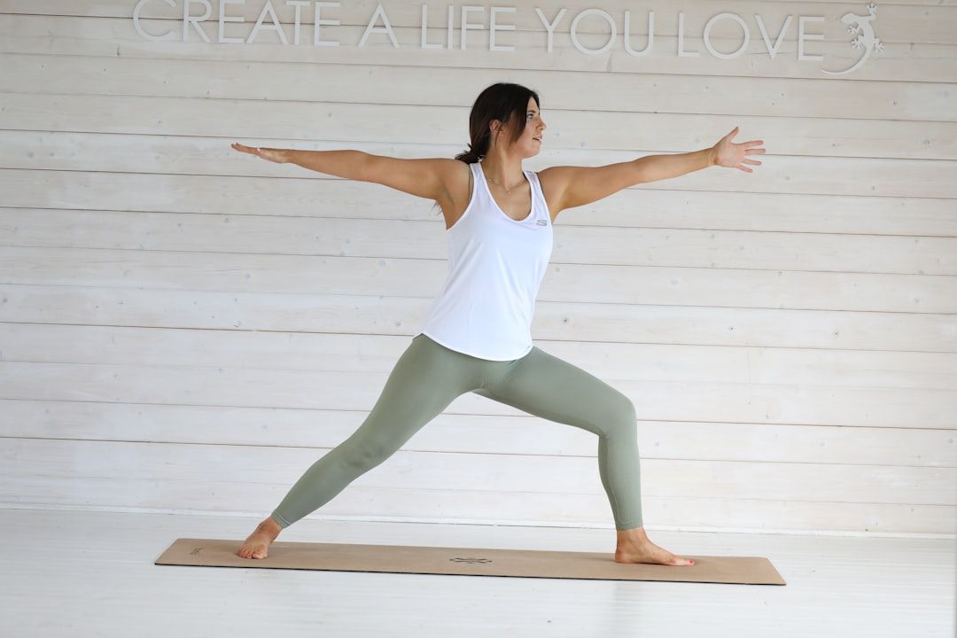 Woman holding warrior two pose on a cork mat in a bright white studio