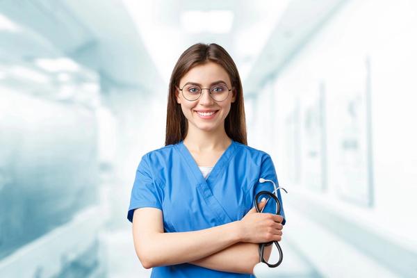 Smiling practitioner in blue scrubs holding a stethoscope in a bright clinic hallway