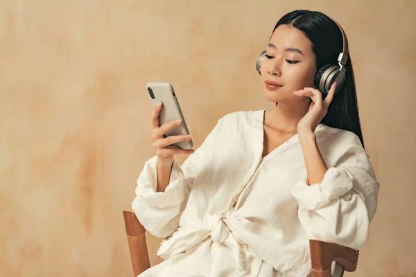 Woman relaxing in a chair with headphones on, following a guided session on her phone