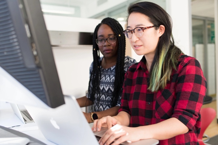 Two women using a computer to check their company metrics