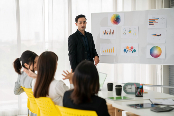 A customer training meeting underway with graphs and figures on a whiteboard