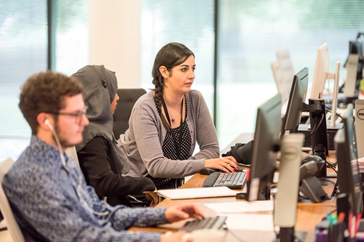 Three customer service representatives working at computers in a help center.