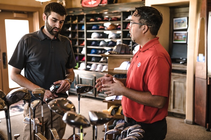 Two men talking in a golfing store about the customer’s needs.