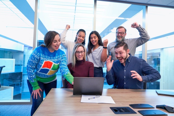 Customer services representatives celebrating at a laptop after delivering some fantastic customer experiences.