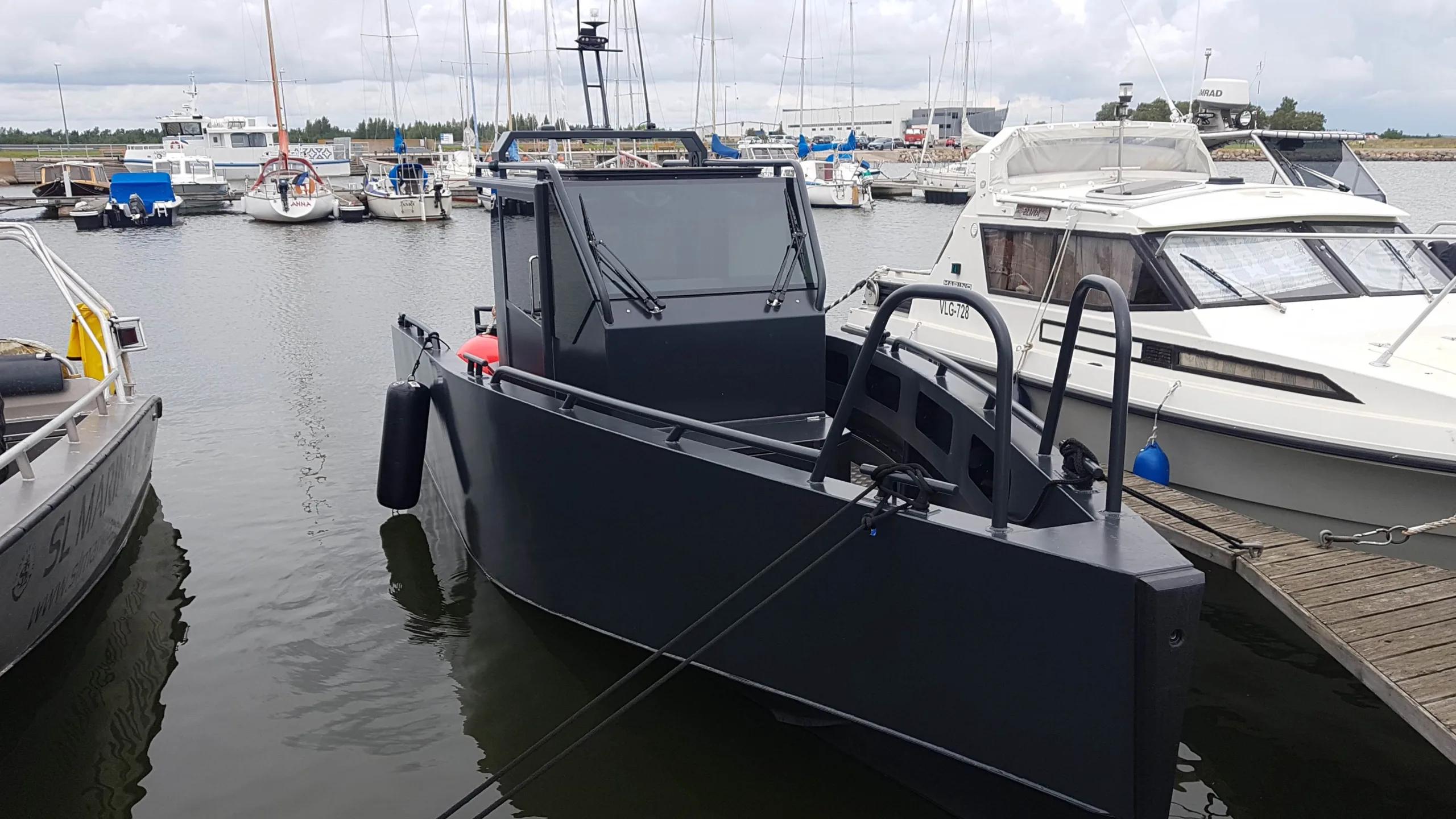 Matte black Ormrin workboat with enclosed cabin moored bow-to a marina pontoon