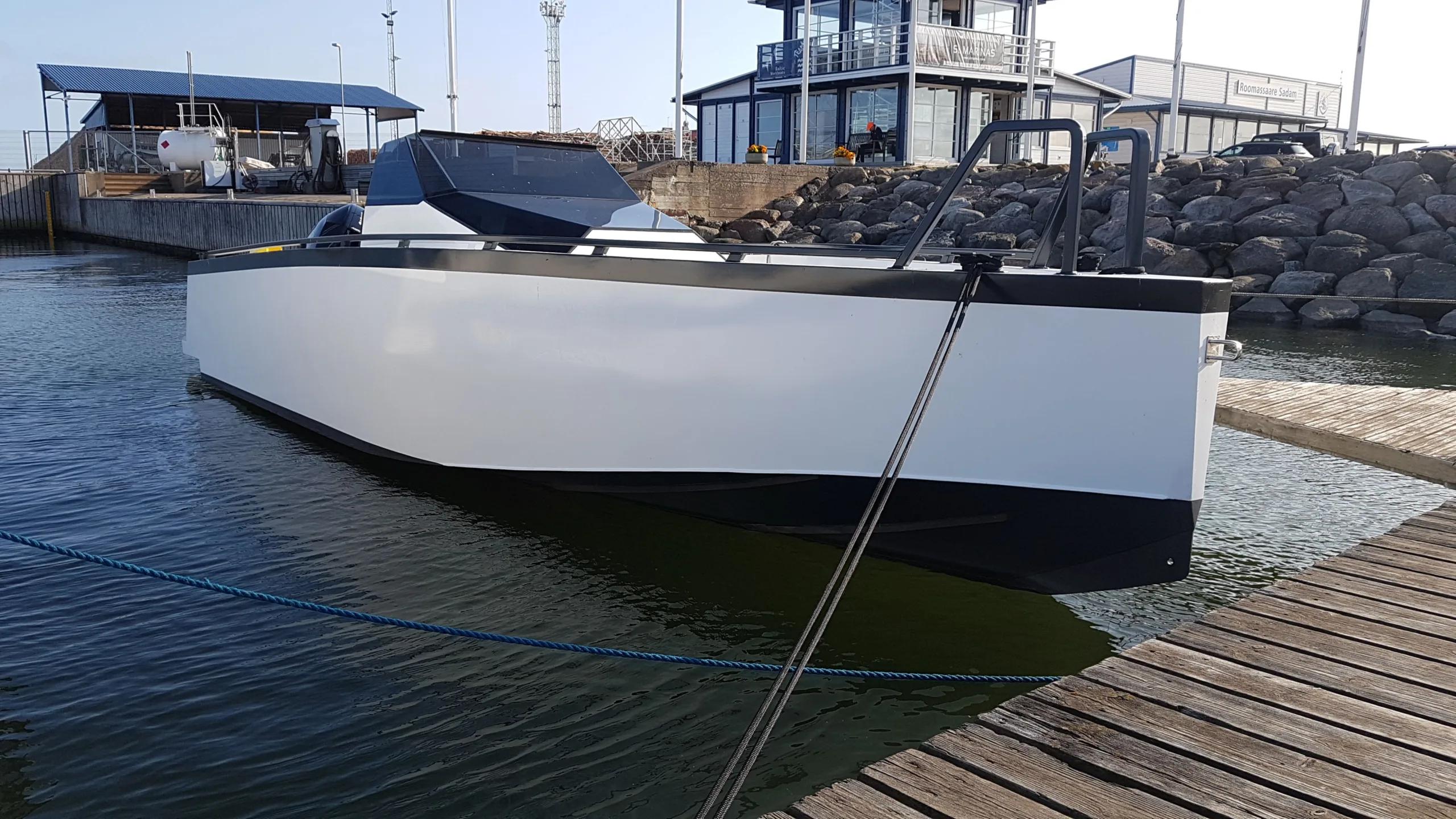 Custom white workboat berthed bow-on at Roomassaare harbour behind a rock breakwater