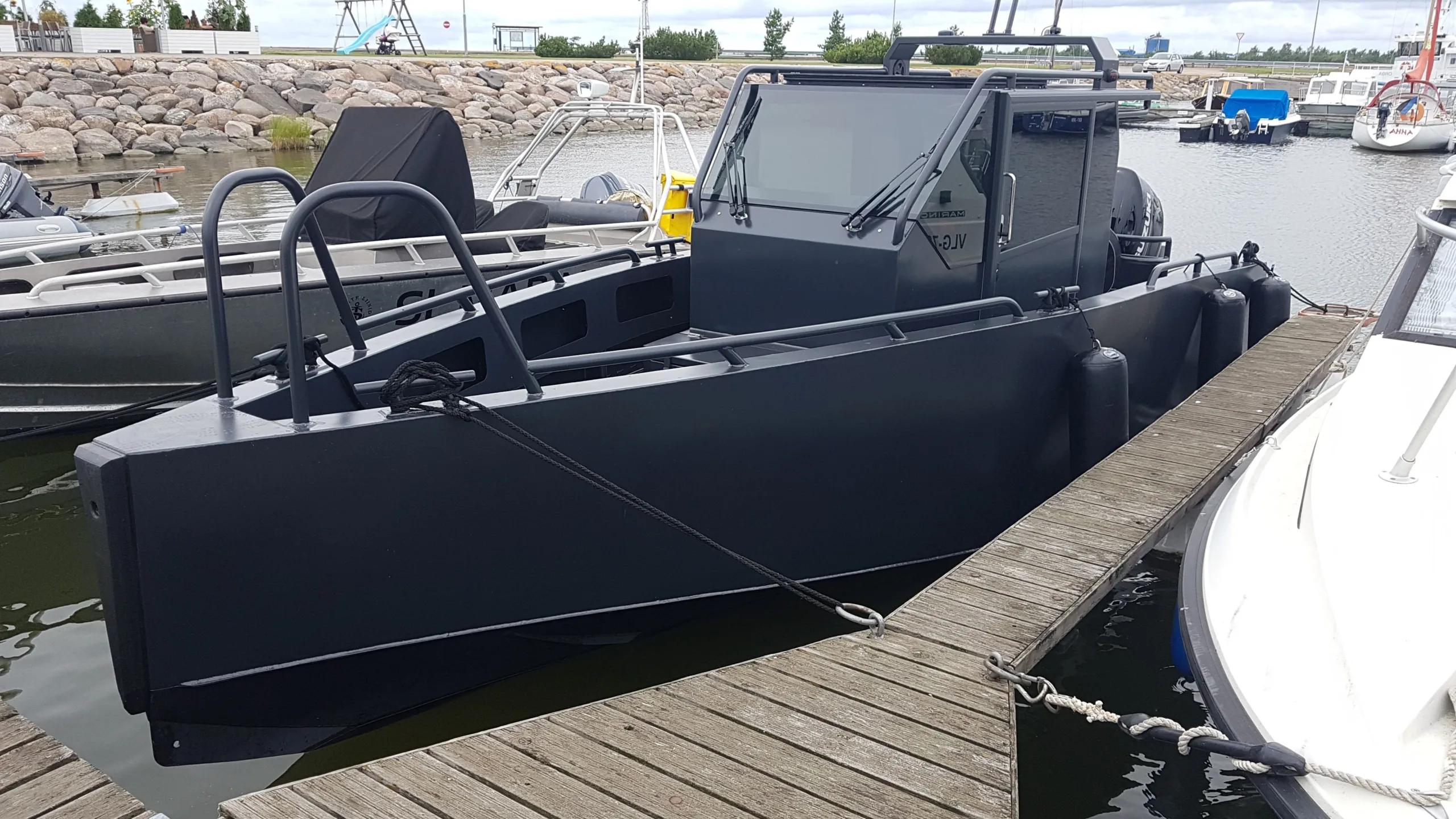 Cabin workboat alongside a pontoon, outboard on the transom, rock breakwater behind
