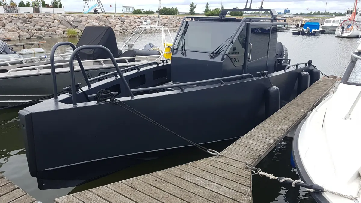 Cabin workboat alongside a pontoon, outboard on the transom, rock breakwater behind