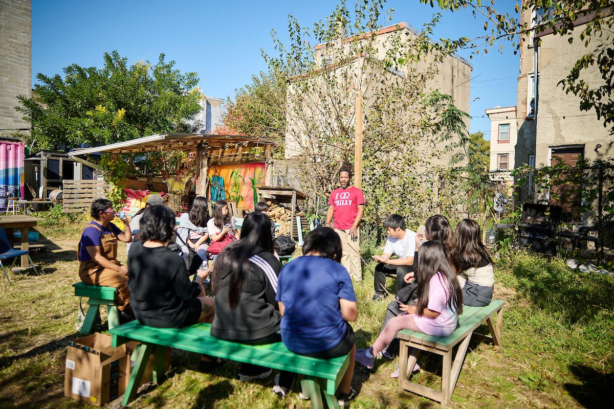 Photo courtesy of Albert Yee. Students and teachers sit on benches and listen to speaker at Inglesias Garden.