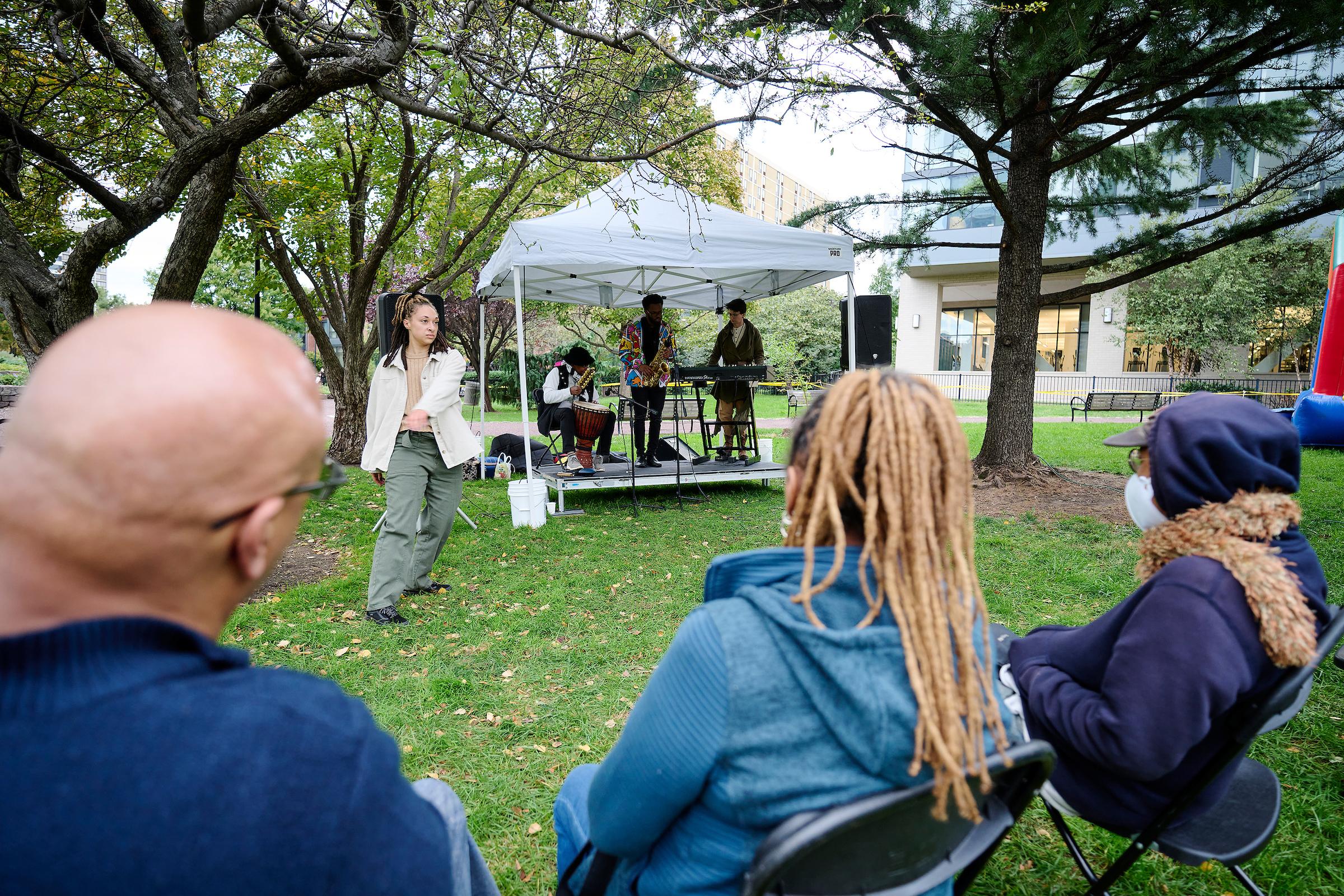 Photo courtesy of Albert Yee. People watch performance at block party, women is dancing to music.