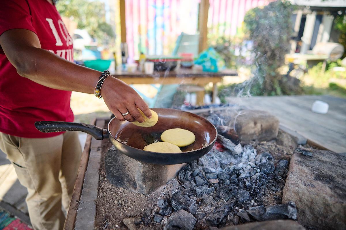 Photo courtesy of Albert Yee. Person preparing food on a pan above a fire.