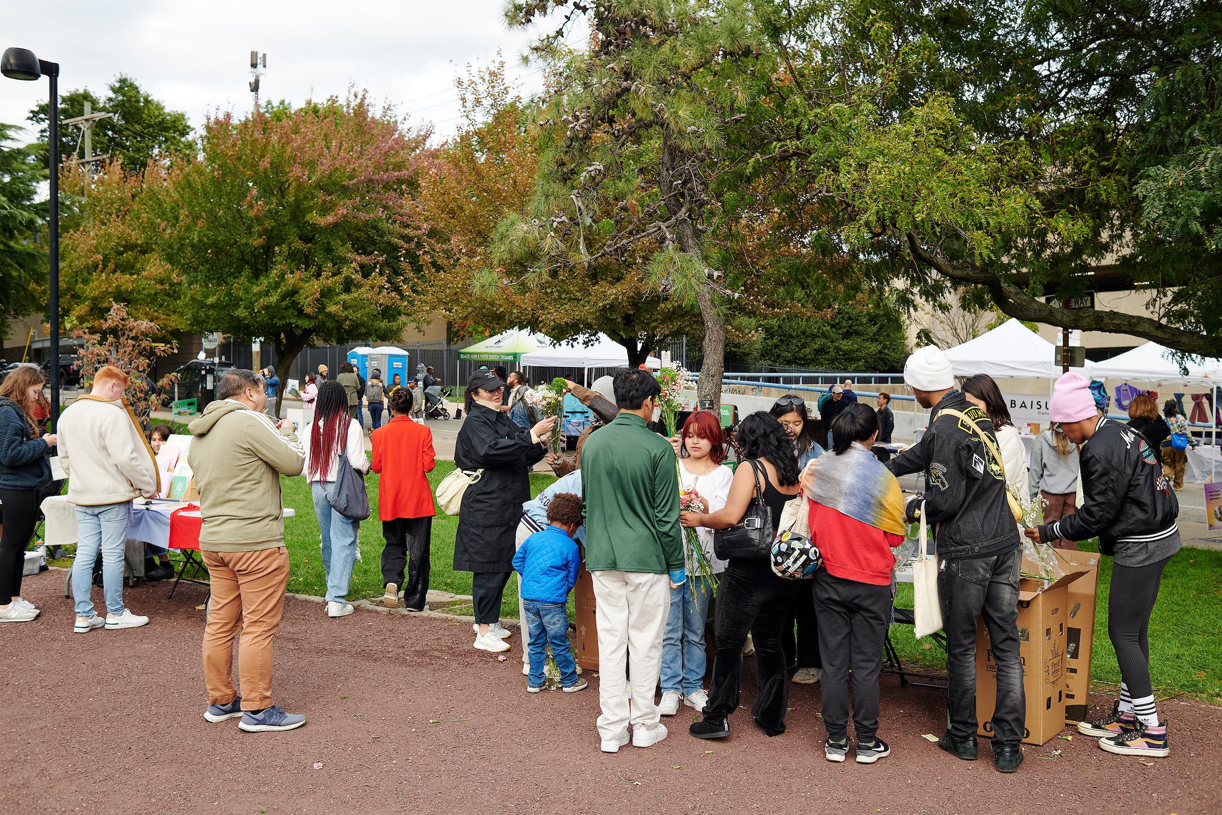 Photo by Albert Yee. Crowds of people gather around different vendors in a park.