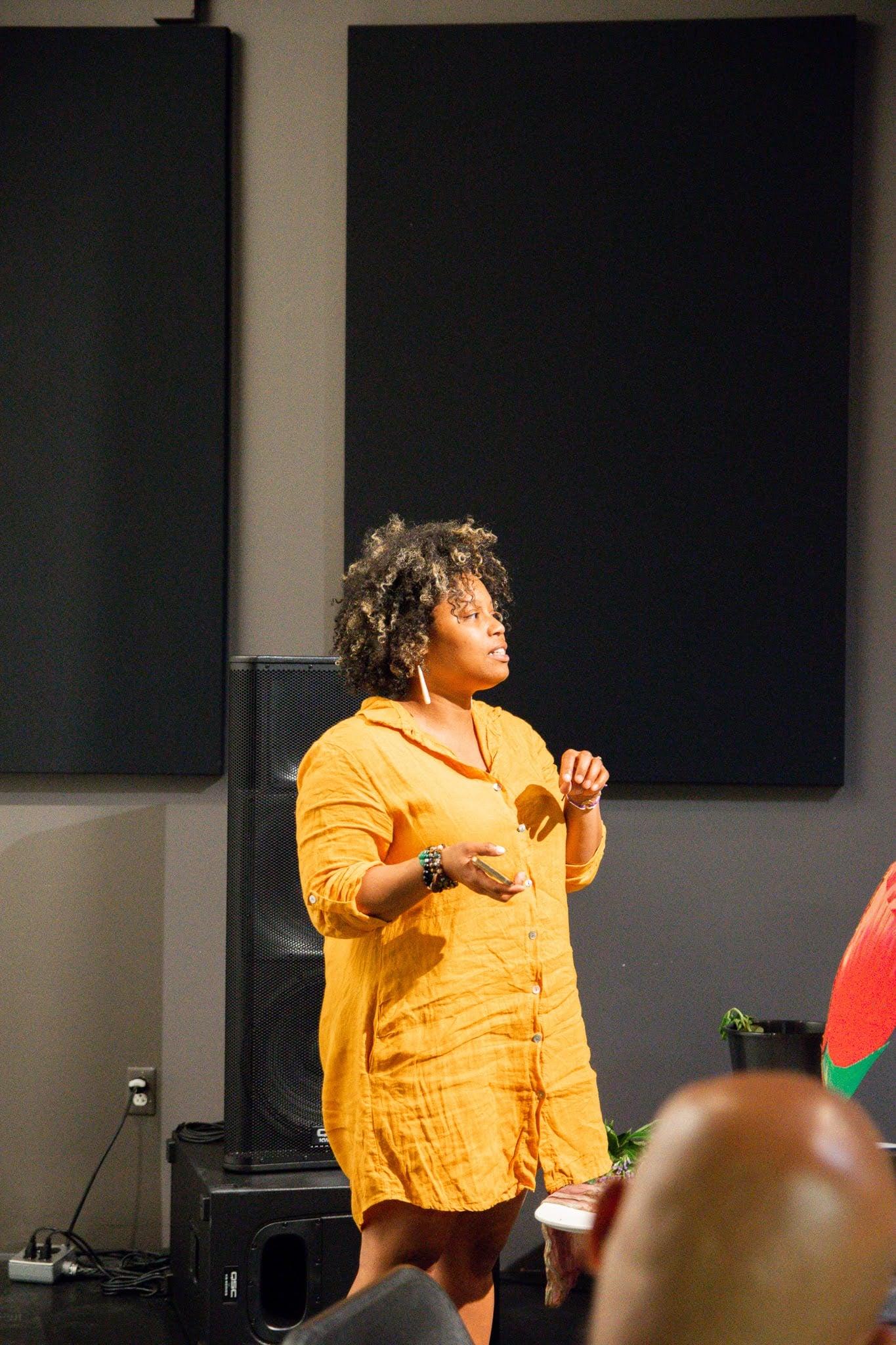 A speaker in a yellow dress at the Fall dinner