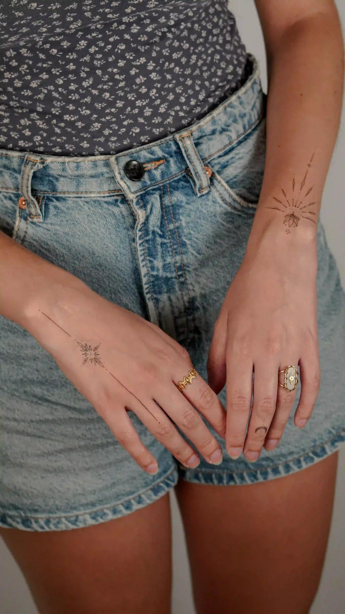 Ornamentales Fineline-Tattoo einer Sonne an Hand und Handgelenk