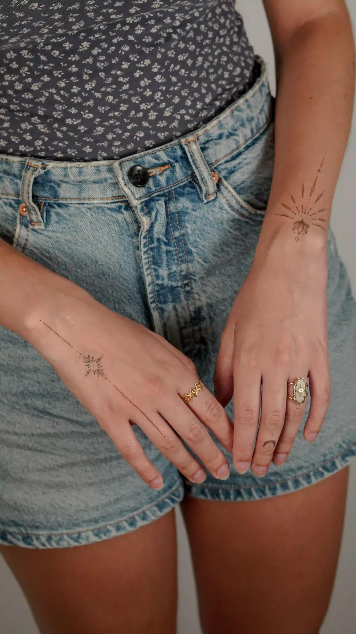 Ornamentales Fineline-Tattoo einer Sonne an Hand und Handgelenk
