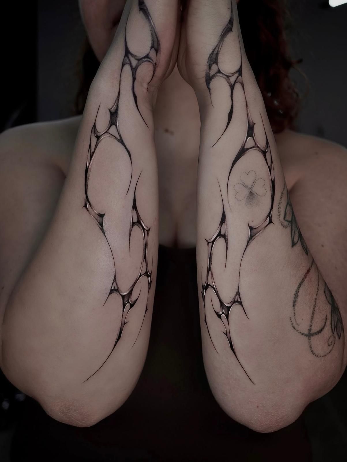 Abstrakte Tattoos an beiden Unterarmen: organische, netzartige Linien mit glänzender Schattierung, spiegelbildlich gestochen