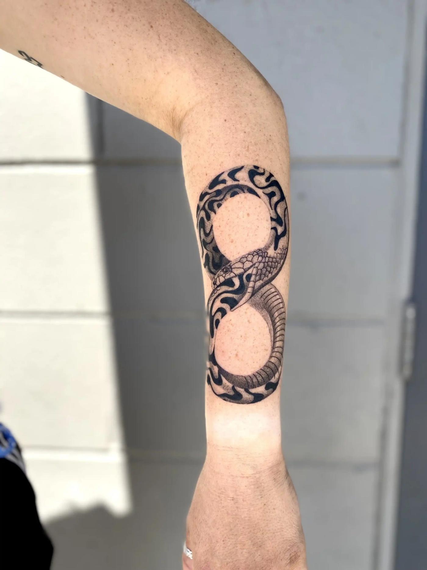 Blackwork-Tattoo einer Schlange in Unendlichkeitsform (Ouroboros) am Unterarm