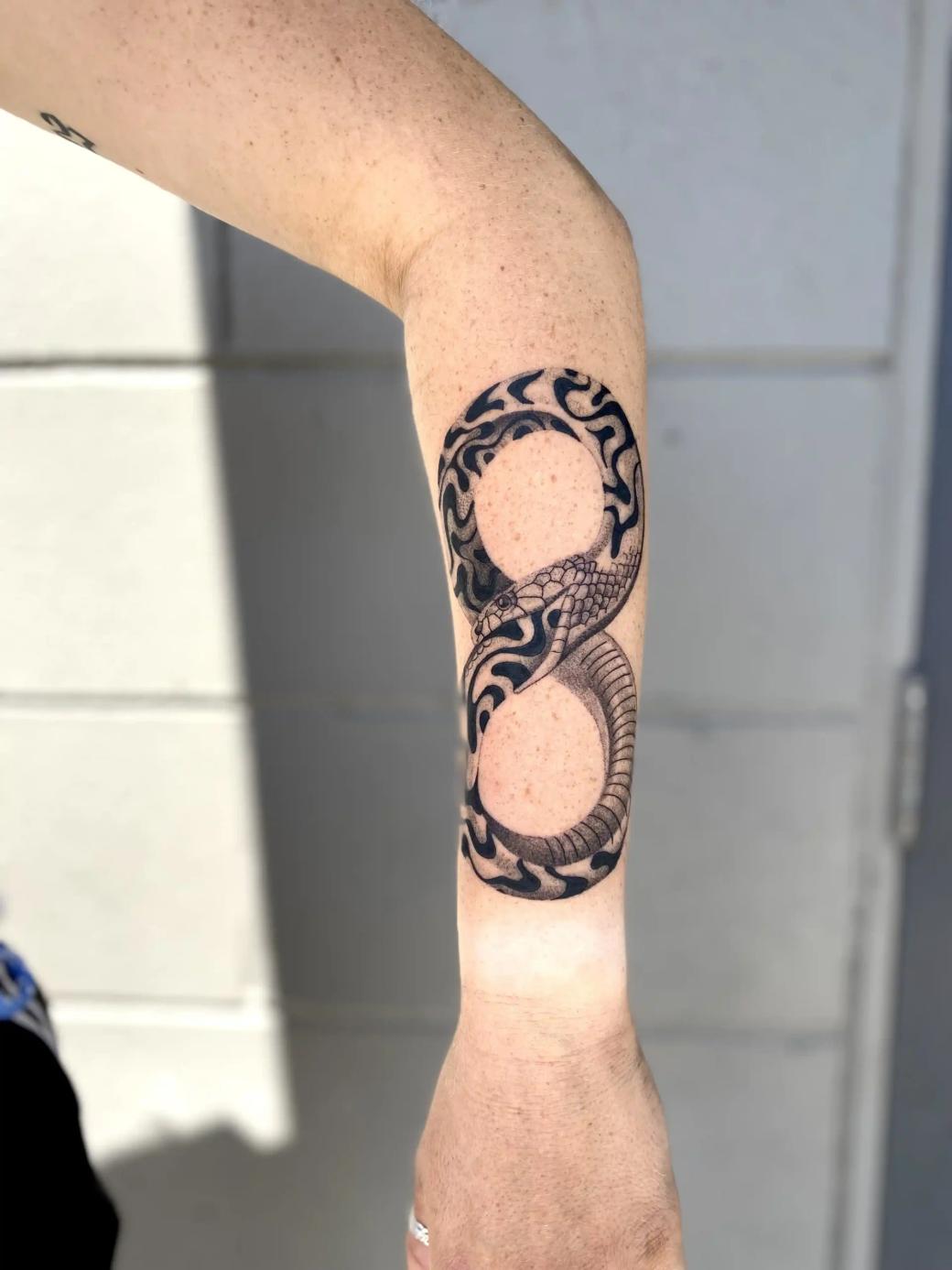 Blackwork-Tattoo einer Schlange in Unendlichkeitsform (Ouroboros) am Unterarm