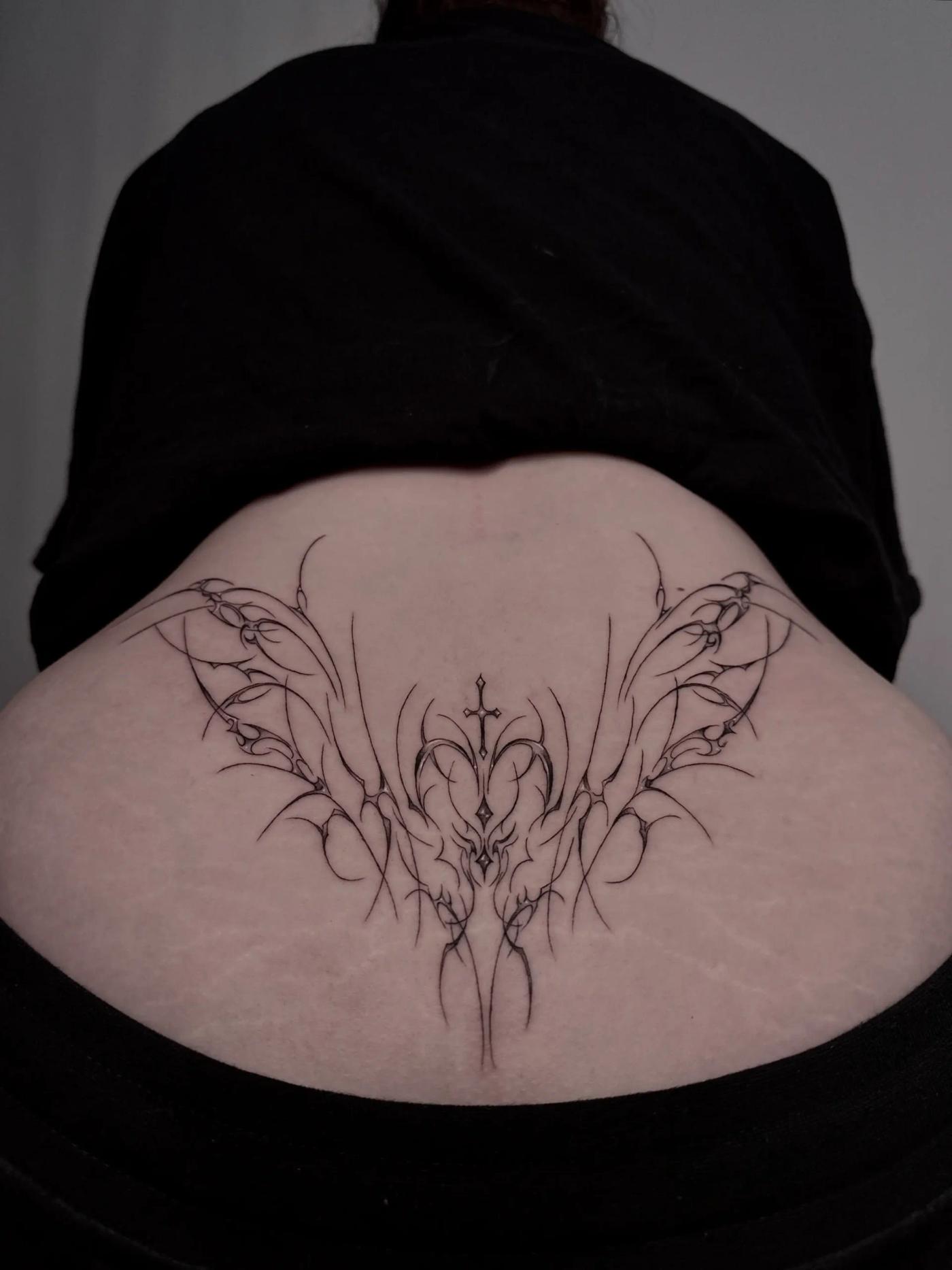 Fineline-Cyber-Sigilism-Tattoo am unteren Rücken in Form abstrakter Flügel, mit symmetrischem Fluss und feinen Details.