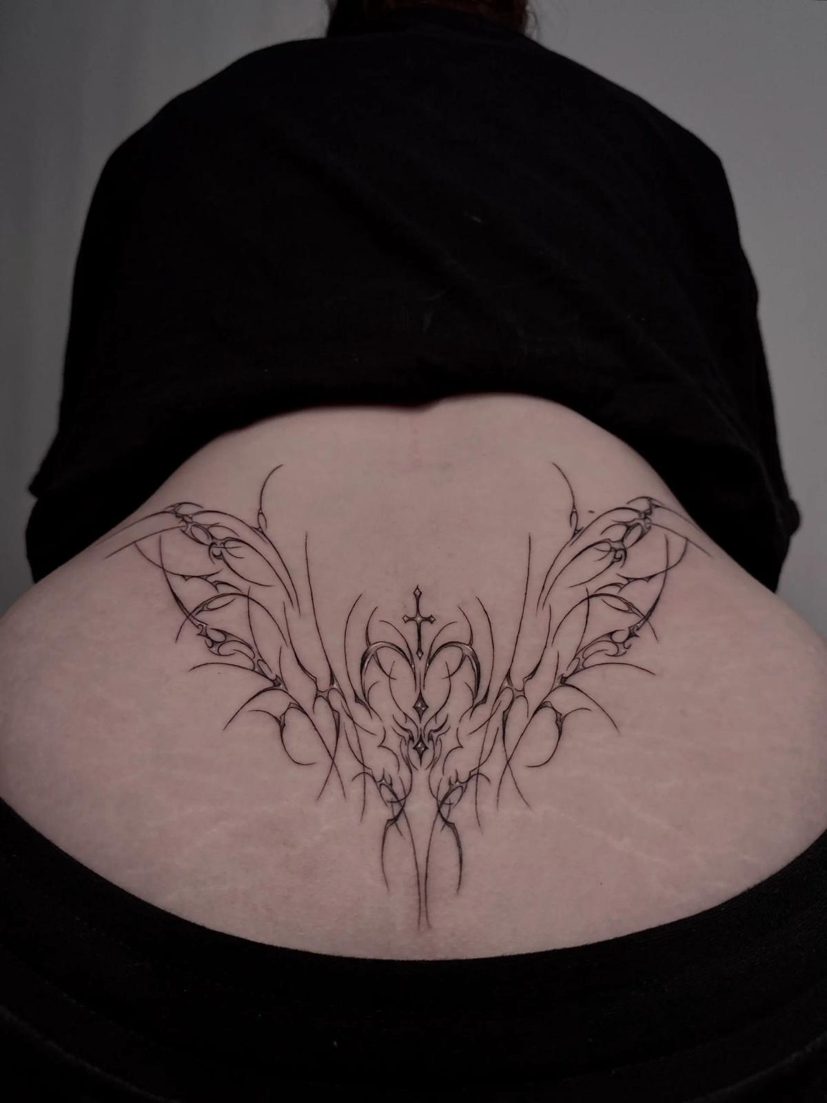 Fineline-Cyber-Sigilism-Tattoo am unteren Rücken in Form abstrakter Flügel, mit symmetrischem Fluss und feinen Details.
