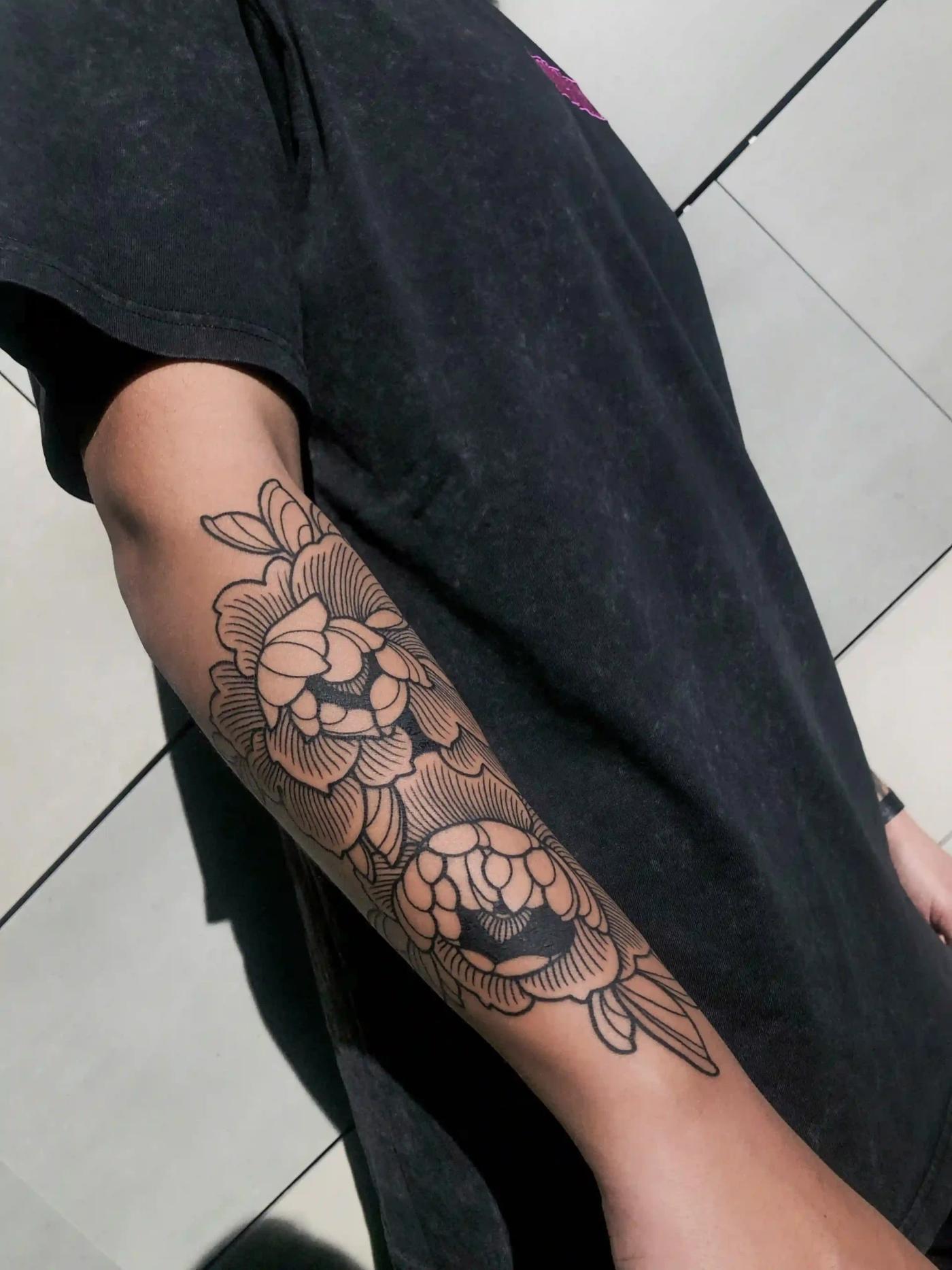 Linework-Tattoo einer Blume am Arm