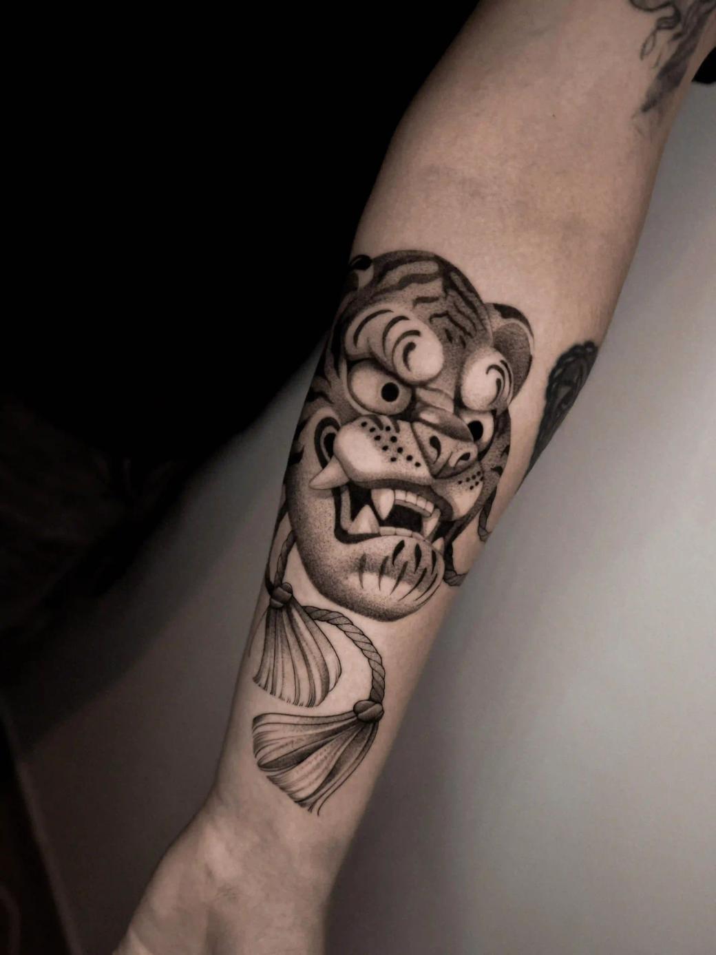 Illustratives Schwarz-Weiß-Tattoo einer Tigermaske an der Unterarm-Innenseite