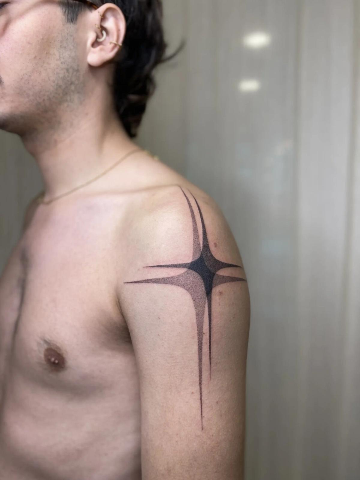 Blackwork-Tattoo eines großen Funkelsterns mit Dotwork-Schattierung an Schulter und Oberarm