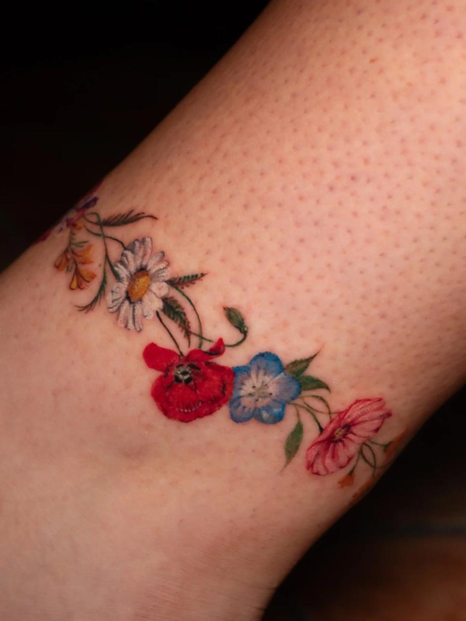 Farbiges Mikrorealismus-Tattoo mit Wildblumen ums Fußgelenk