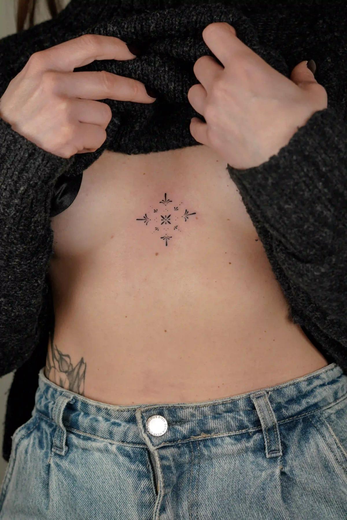 Delicate fine-line ornamental tattoo on the sternum