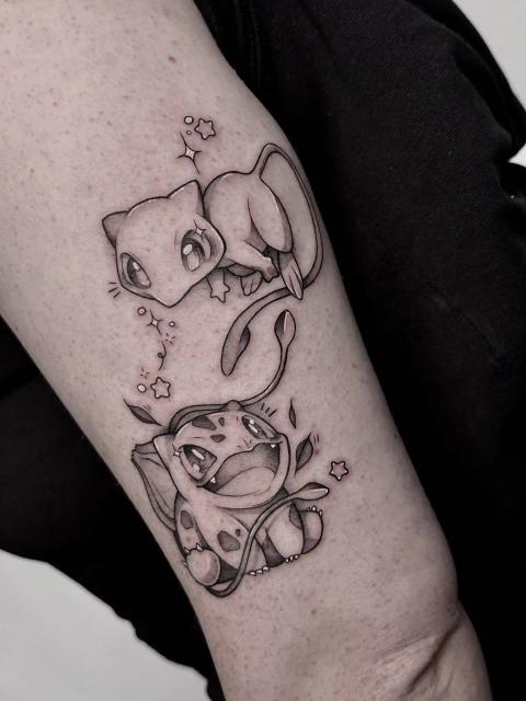 Schwarz-Grau-Tattoo von Mew und Bisasam in niedlichem, anime-inspiriertem Stil mit weicher Schattierung und Sternen-Akzenten am Oberschenkel.