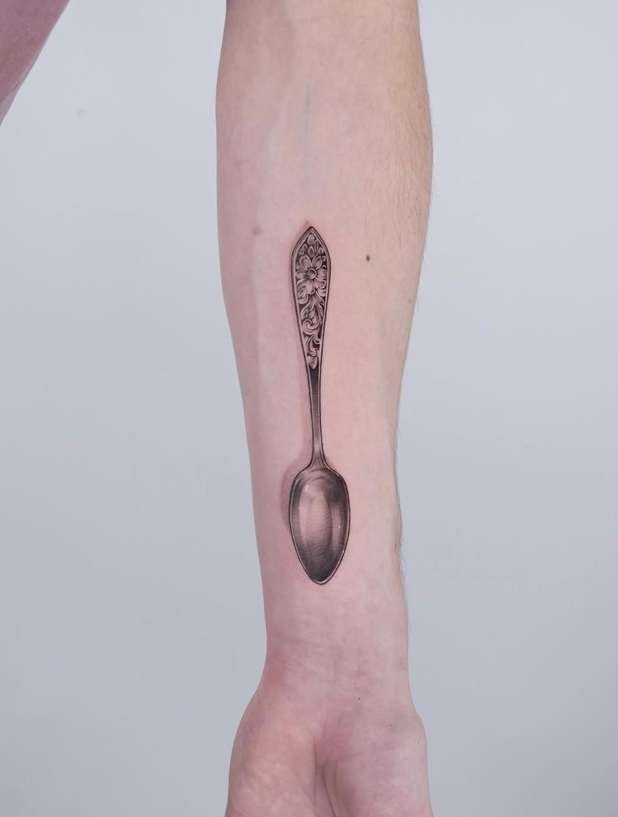 Tattoo am Unterarm: realistisch schattierter Silberlöffel mit floral graviertem Griff