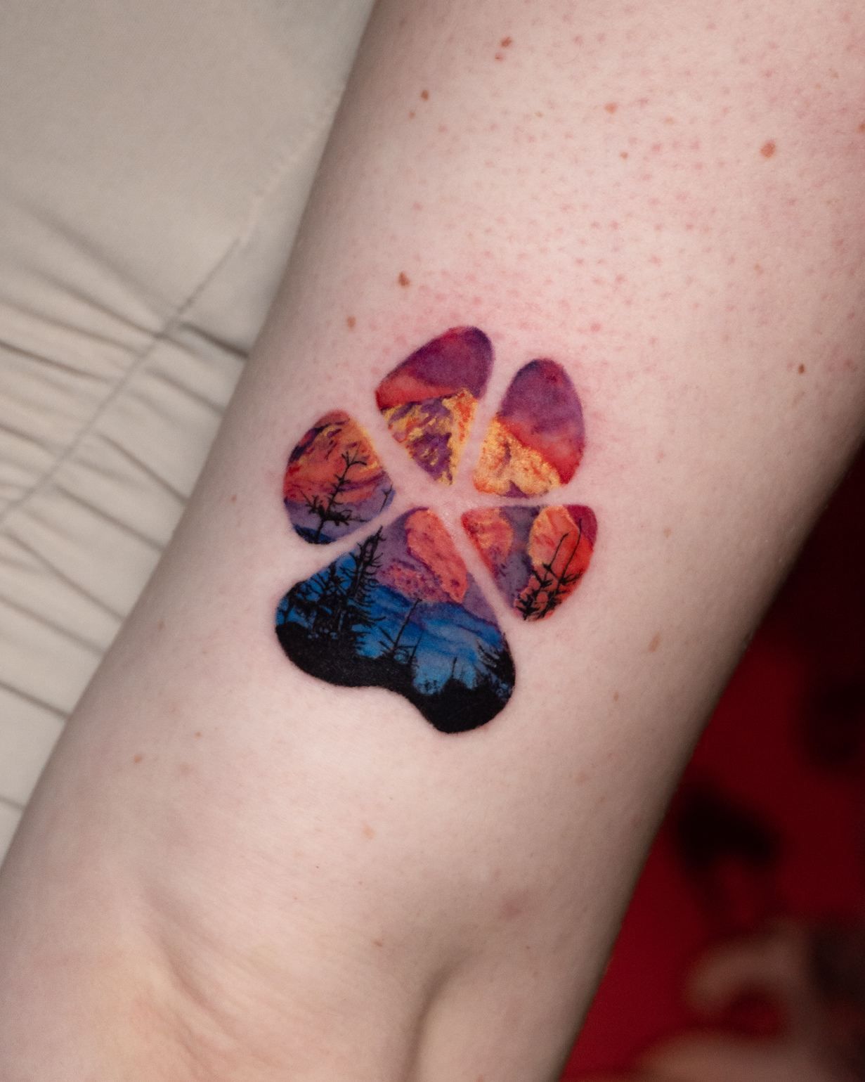 Farb-Mikrorealismus-Tattoo einer Hundepfote mit Bergkette
