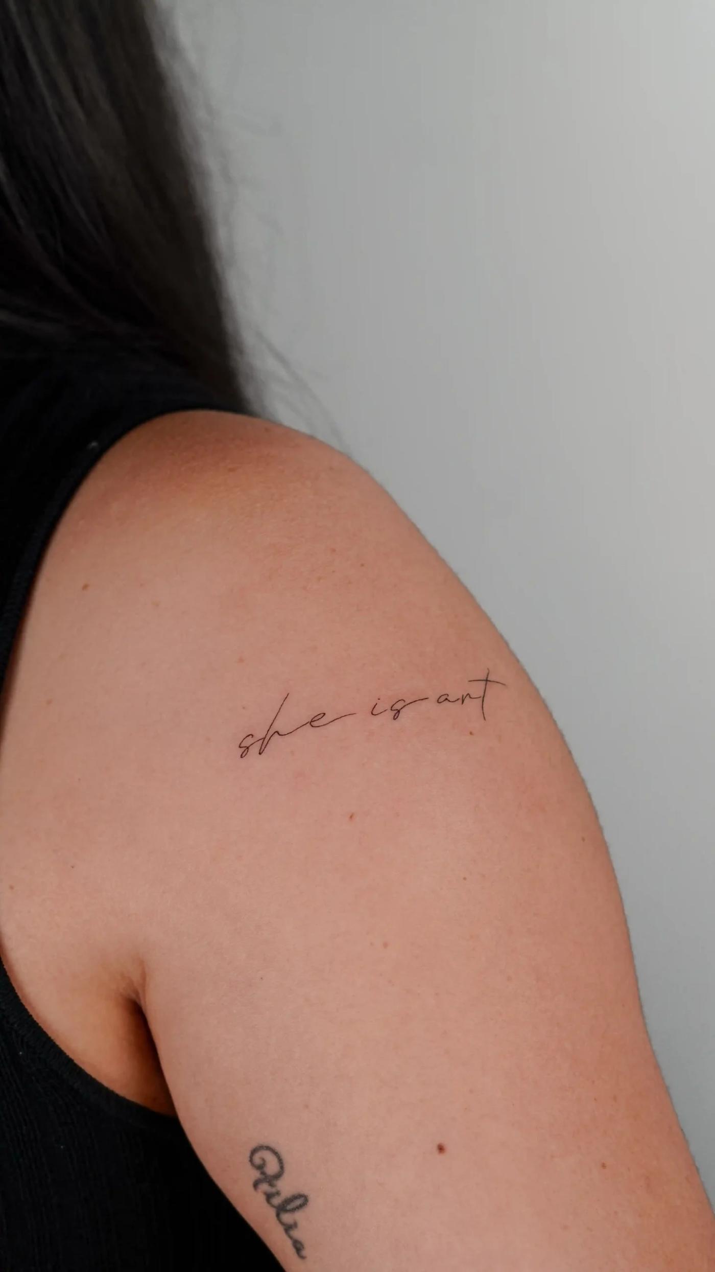 Fineline-Lettering-Tattoo mit dem Schriftzug "she is art"