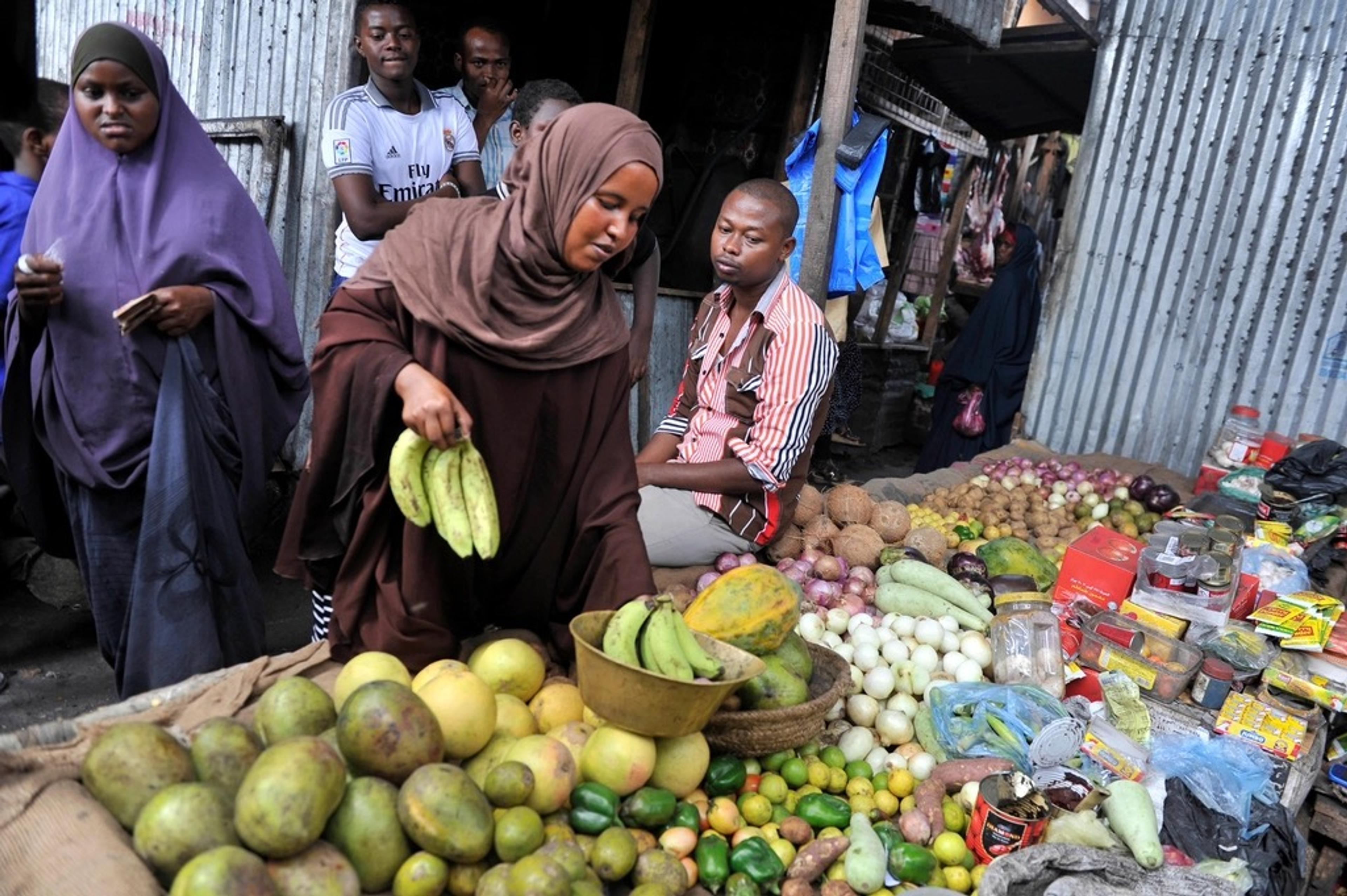 A busy open-air market stall with fruit and vegetables for sale.