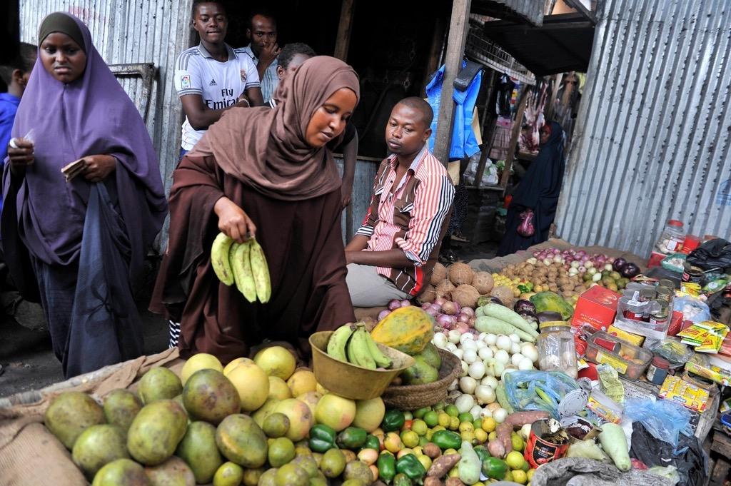 A busy open-air market stall with fruit and vegetables for sale.