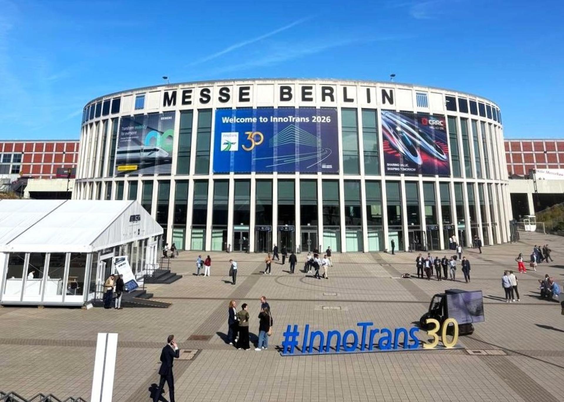 Exterior of Messe Berlin under a clear blue sky, with a “Welcome to InnoTrans 2026” banner and an #InnoTrans30 sign in the plaza.