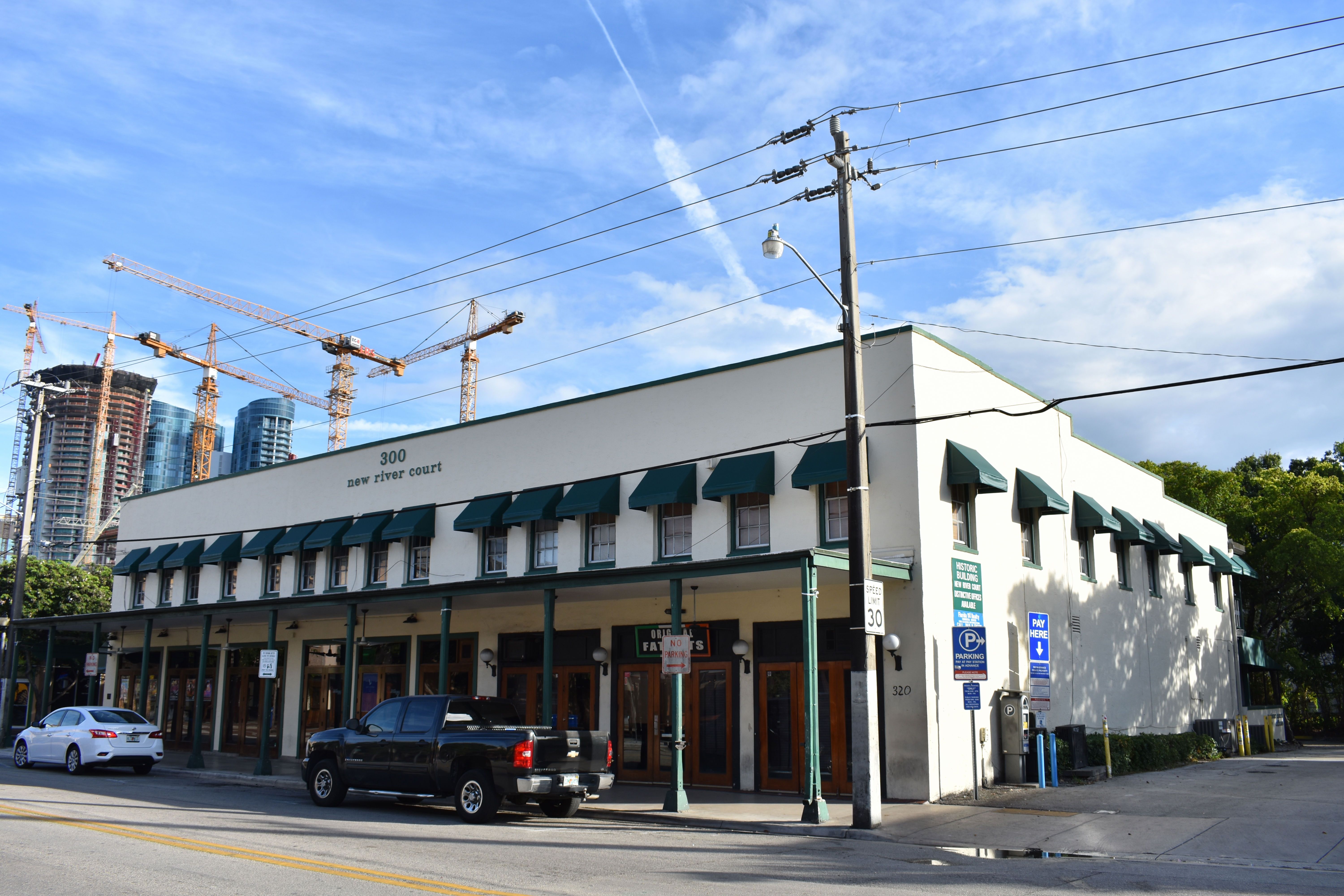 New River Court low-rise commercial building with downtown Fort Lauderdale construction cranes behind it in 2018.