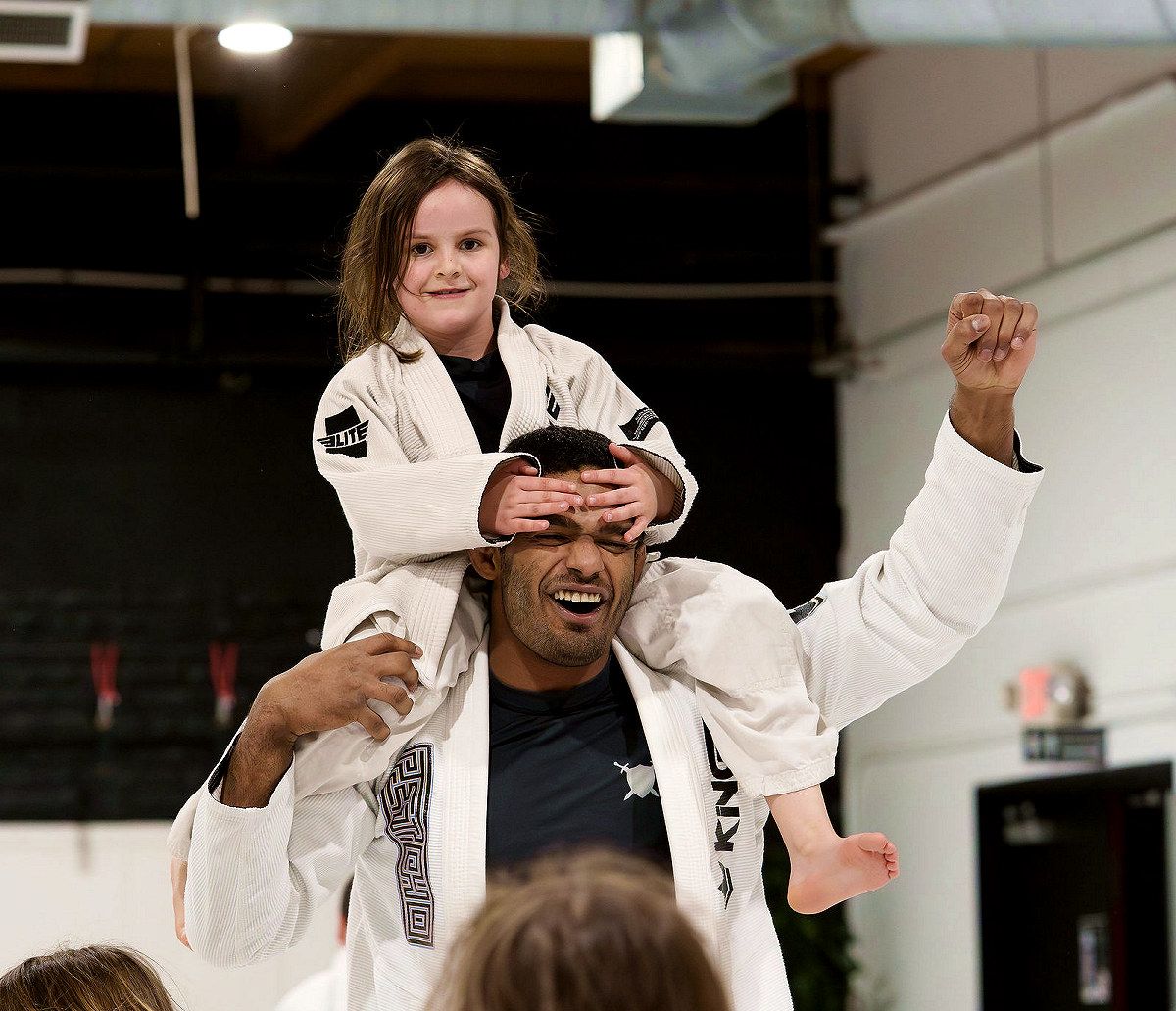 A coach carrying a laughing young student on his shoulders