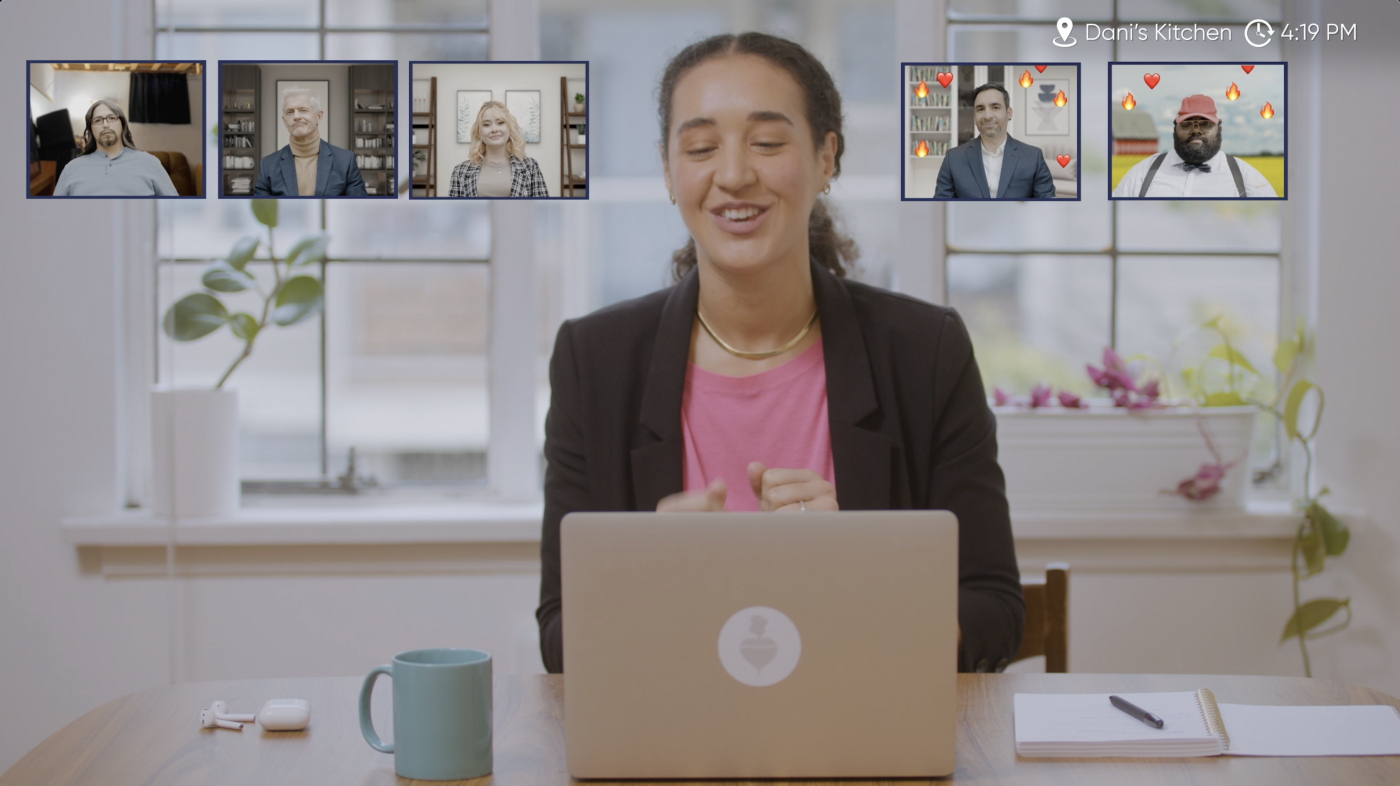 A woman working from home, sitting behind her laptop with her teammates' video tiles floating around her.