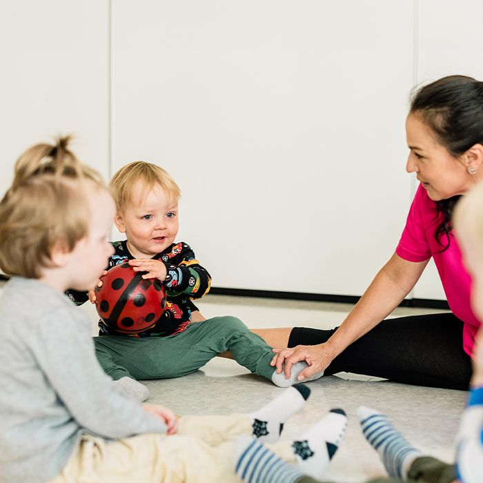 Små barn sitter på gulvet med en voksen