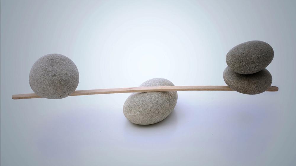 three stones and balance beam, one side with one stone and the other with two
