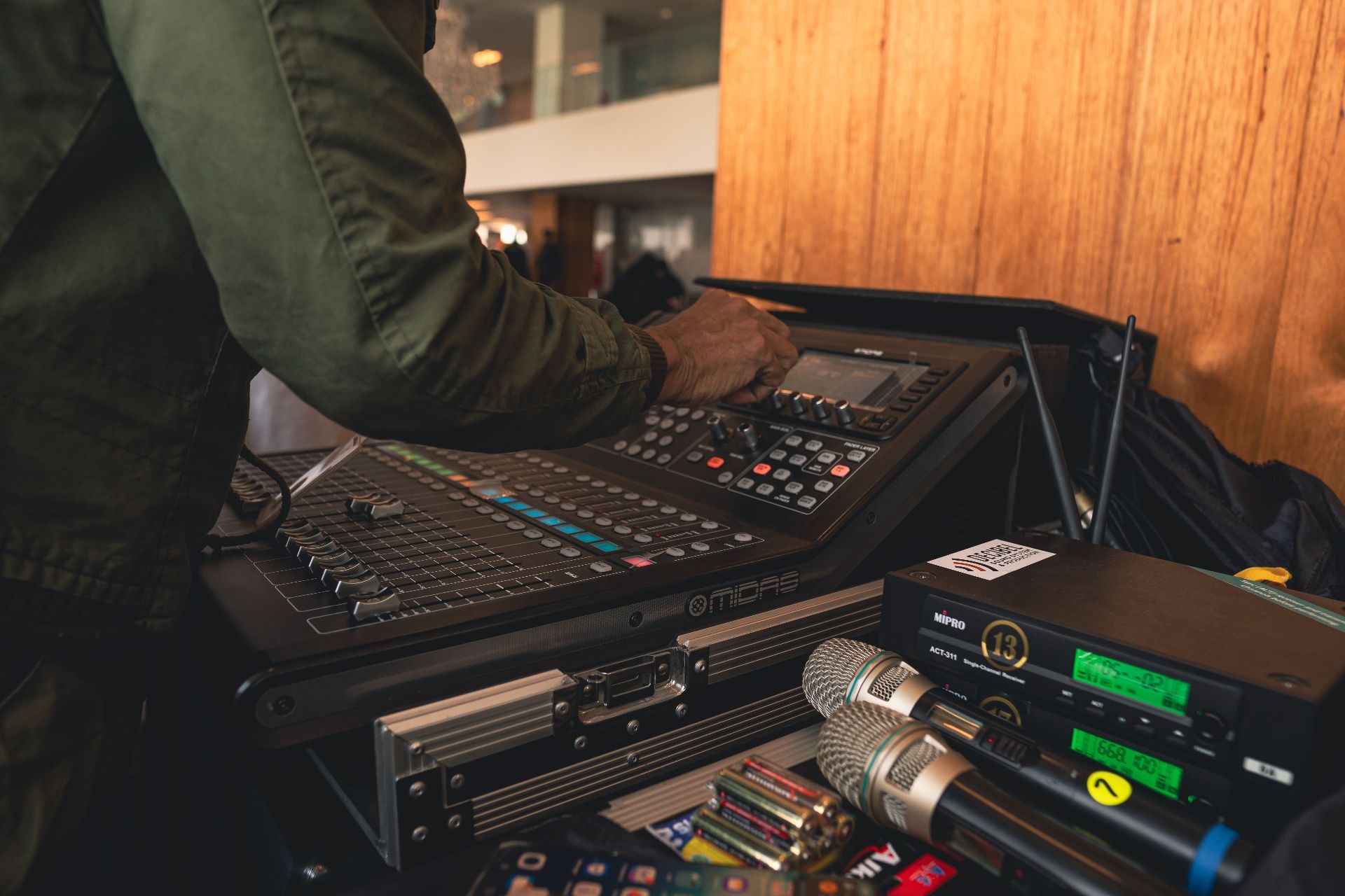 Engineer mixing live audio on a Midas console with wireless microphone receivers