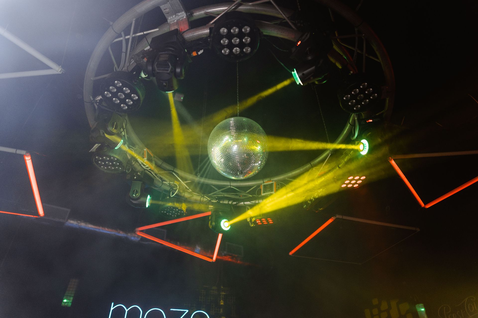 Intelligent lighting rig with moving heads, beams, and mirror ball above a packed dance floor