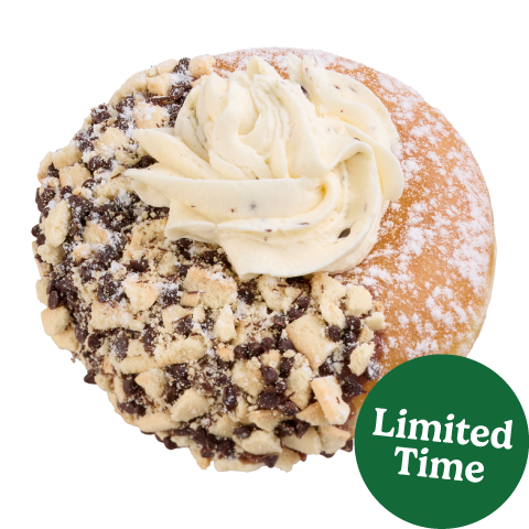 Indulge in a sweet twist on this Italian classic dessert. The Cannoli Inspired Doughnut starts with an unglazed ring, half-dipped in indulgent chocolate icing and irresistible cookie crunch, dusted with a powdered sugar coating, and finally topped with a dollop of cannoli flavored buttercreme. This delicious blend of creamy, crunchy, and sweet is perfect for satisfying your sweet cravings.   