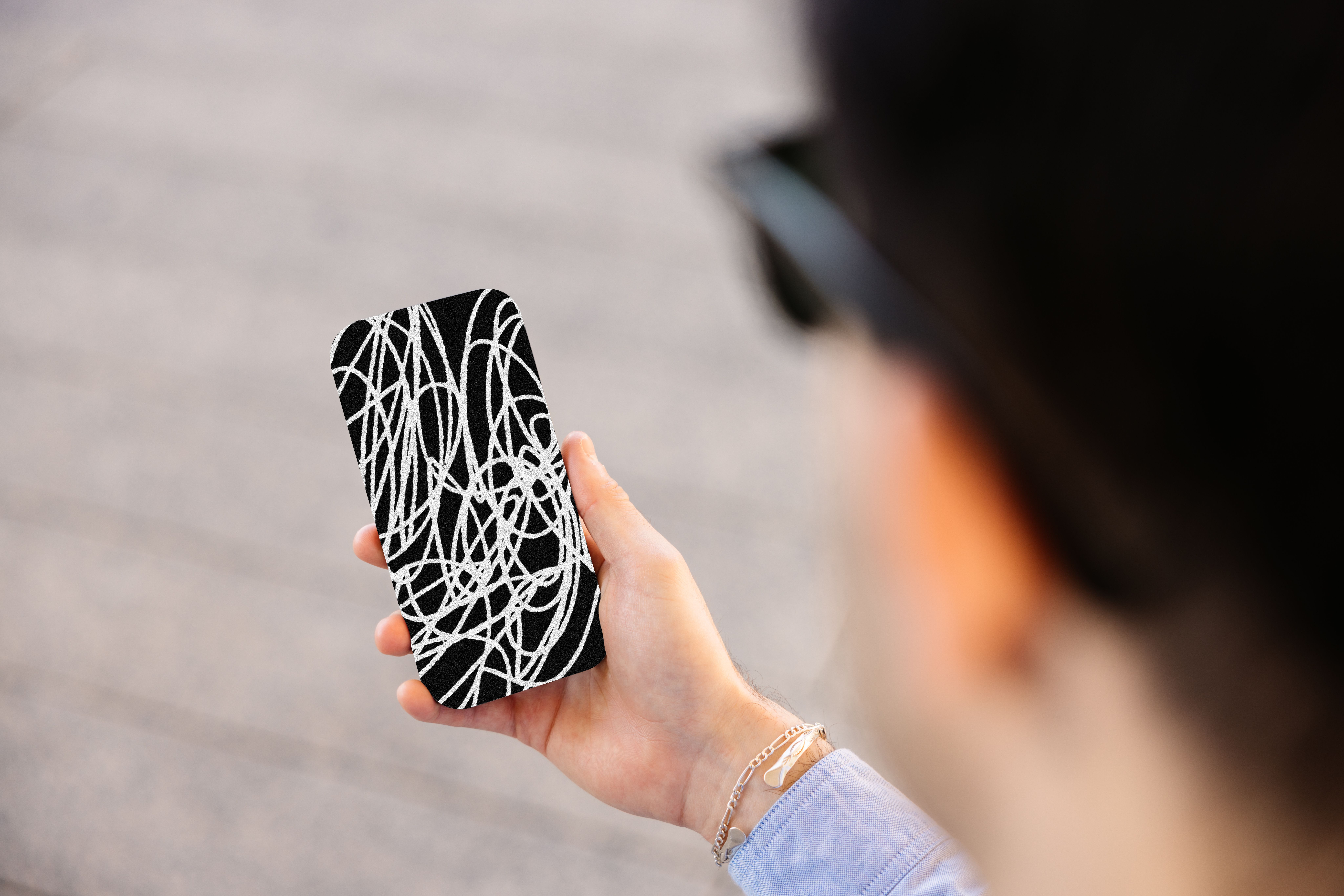 A person holding a phone obscured by scribbles.
