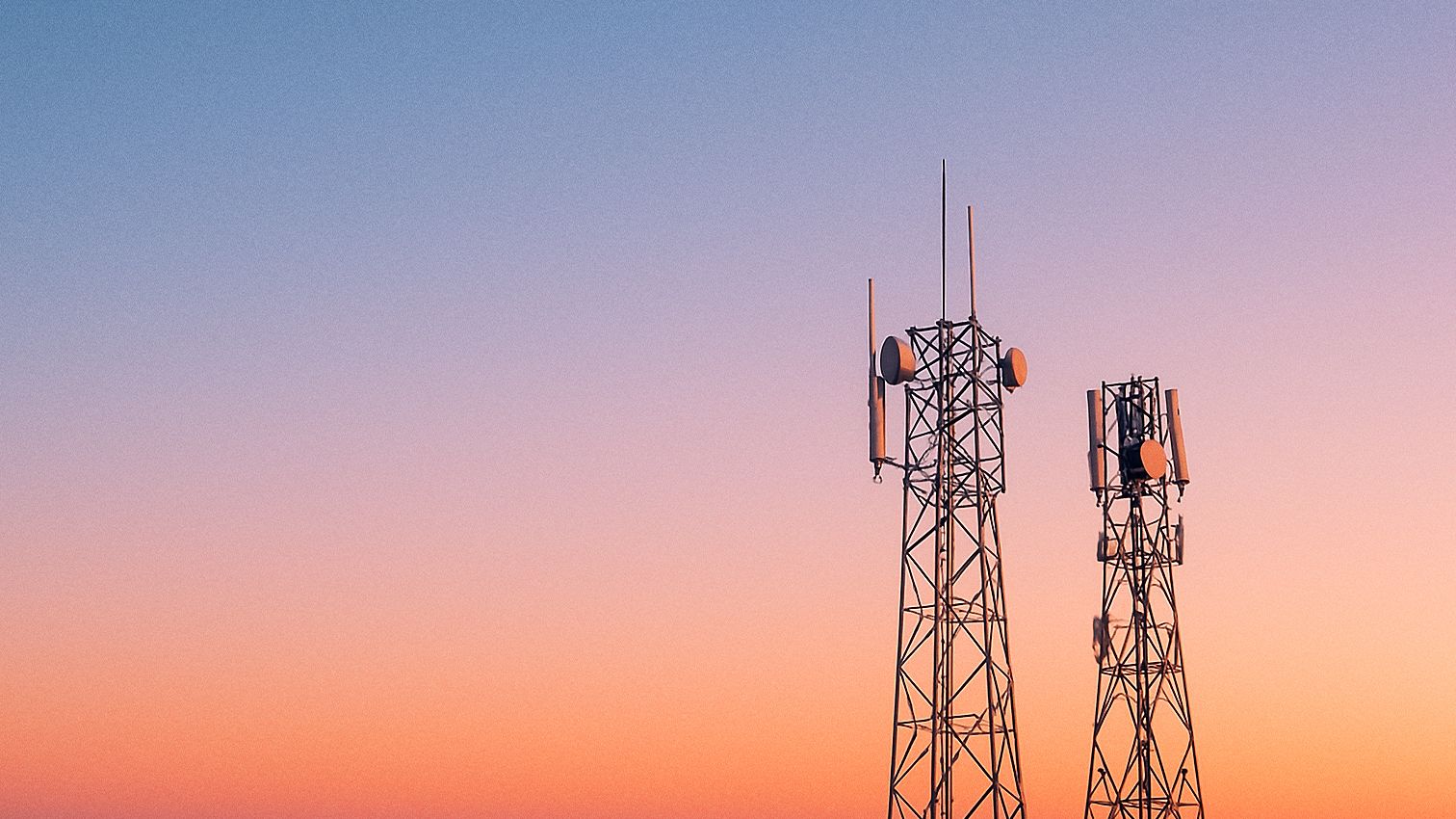 two towers with a sunset behind them.