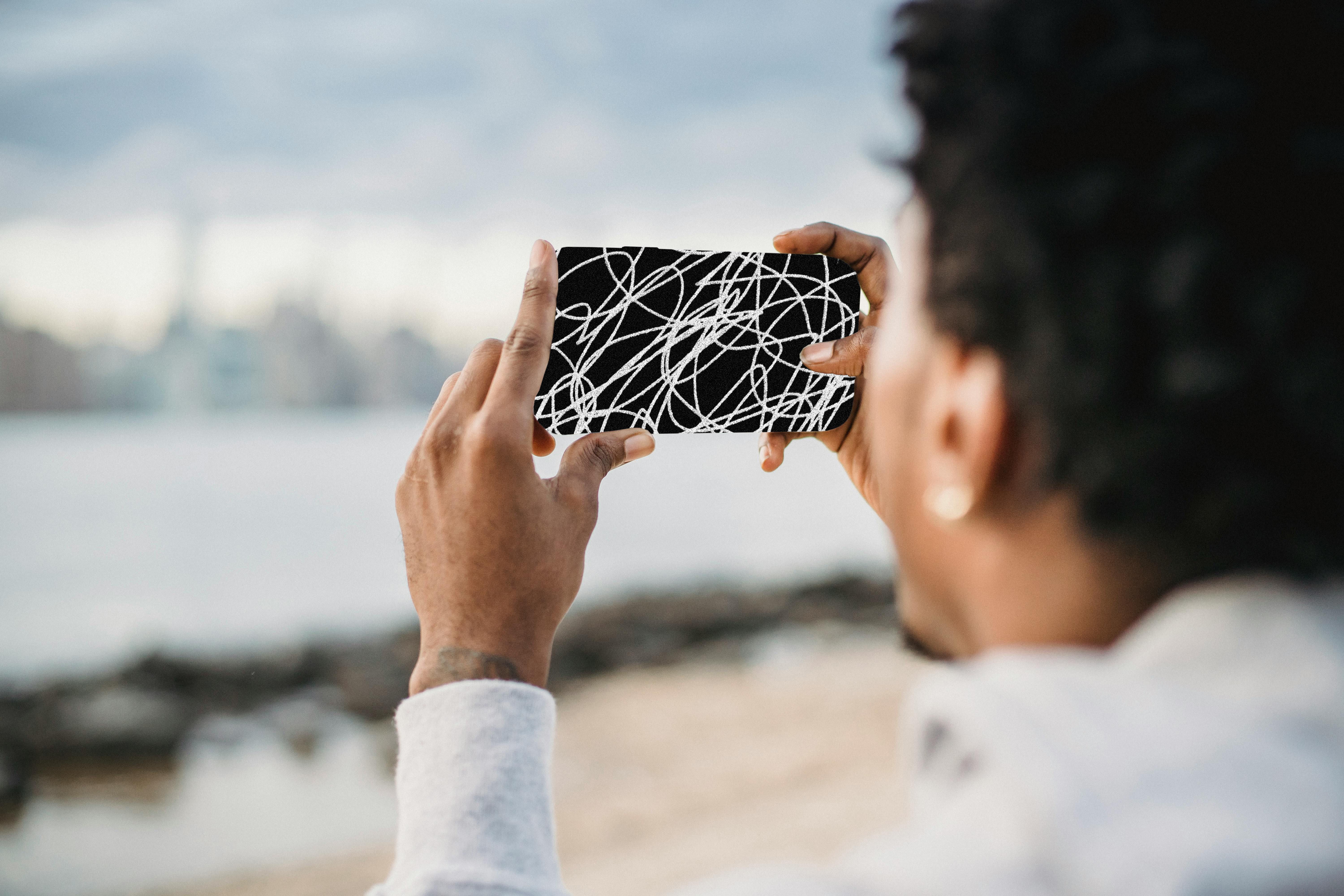 Blurred-out person holding a scribbled out phone, taking a photo of a city skylin