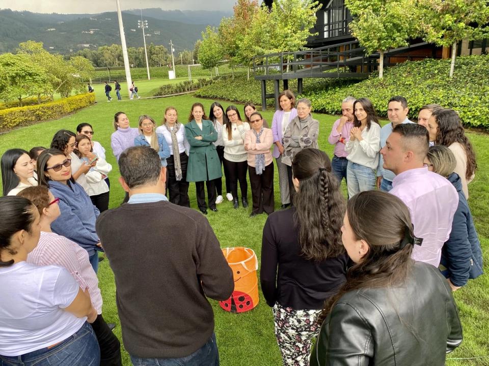 Participantes de un taller al aire libre reunidos en círculo sobre el césped