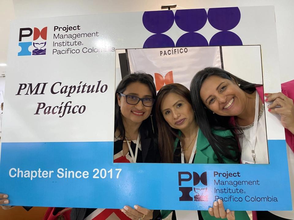 Tres integrantes del PMI Capítulo Pacífico Colombia posan con el marco del capítulo
